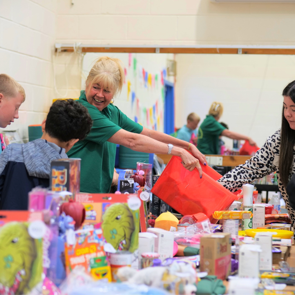 Staff member handing out toys to children at a community fayre