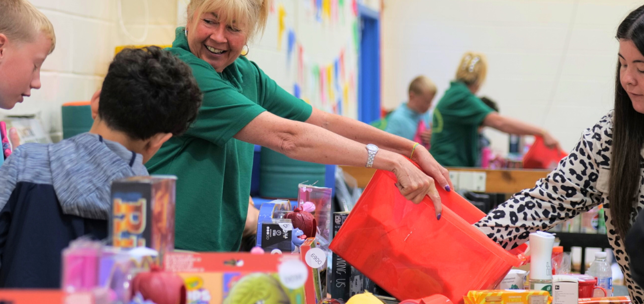 Staff member handing out toys to children at a community fayre