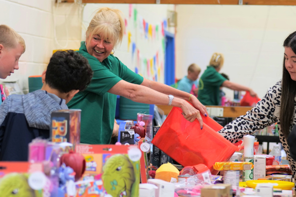 Staff member handing out toys to children at a community fayre