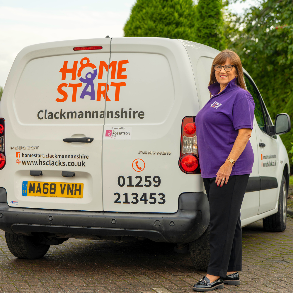 Home-Start staff member standing in front of their organisations branded vehicle 