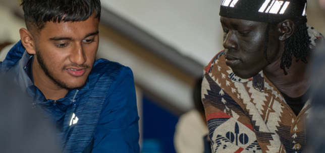 Two young adults in a classroom setting looking at information on paper together