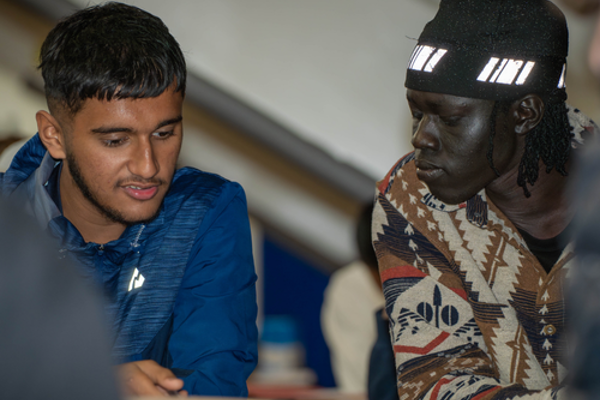 Two young adults in a classroom setting looking at information on paper together
