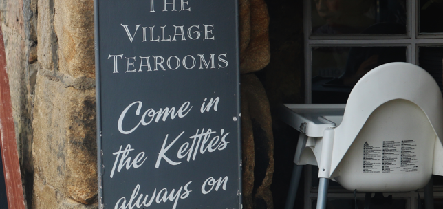 Entrance sign to a coffee shop that says 'The Village Tearooms, come in, the kettles always on'