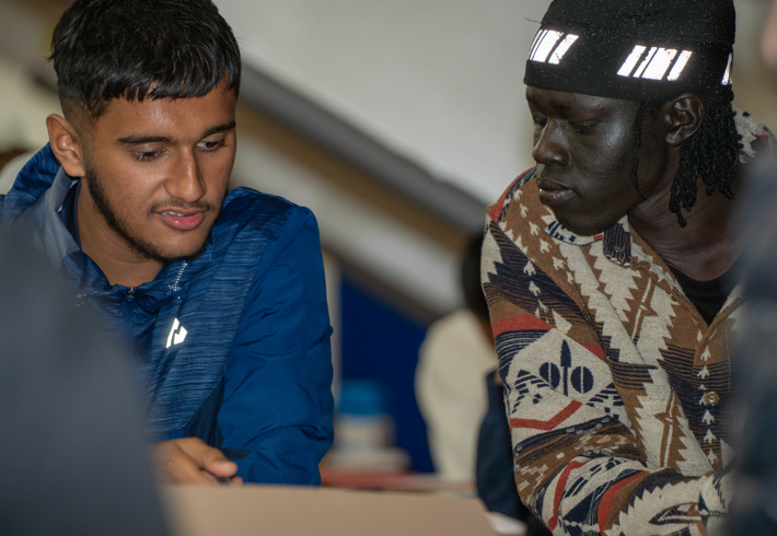 Two young adults in a classroom setting looking at information on paper together