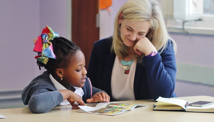 Businesswoman reading with schoolgirl, part of Business in the Community initiative